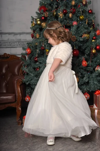 Uma menina em um vestido branco e um casaco de pele está girando em um dr branco — Fotografia de Stock