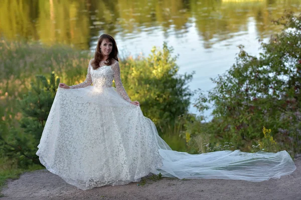 Mulher em um vestido branco com um trem longo no verão em um moun — Fotografia de Stock