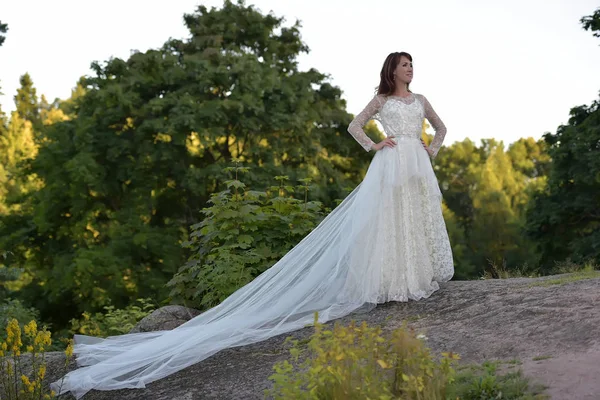 Mulher em um vestido branco com um trem longo no verão em um moun — Fotografia de Stock