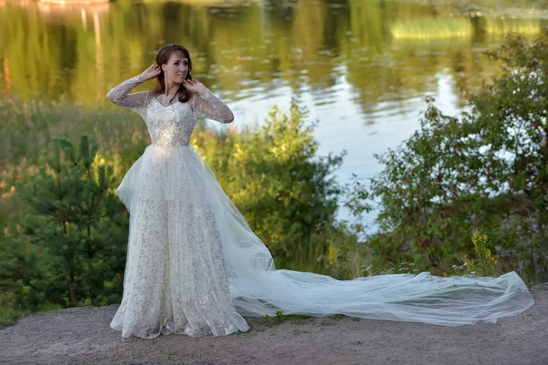 Mulher em um vestido branco com um trem longo no verão em um moun — Fotografia de Stock