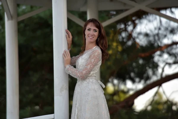 Una mujer con un vestido blanco en el parque en el cenador —  Fotos de Stock