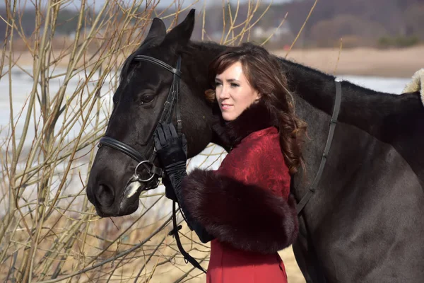 Женщина в красном длинном платье с лошадью в природе — стоковое фото