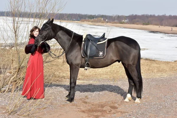 Žena v červených dlouhých šatech s koněm v přírodě — Stock fotografie