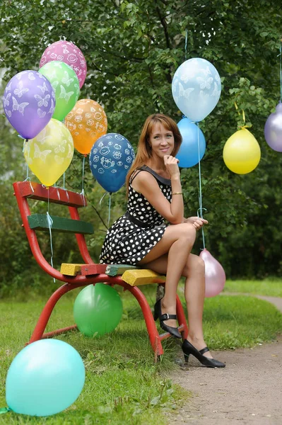 Kobieta w sukience w kropki w parku z balonami latem — Zdjęcie stockowe