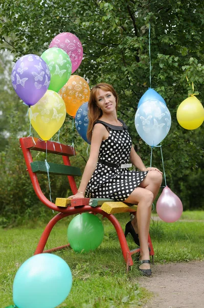 Woman in polka-dot dress in a park with balloons in summer — Stock Photo, Image