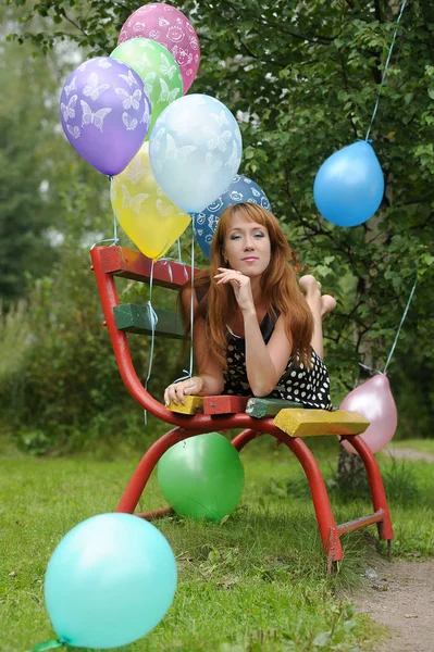 Kvinna i polka-dot klänning i en park med ballonger på sommaren — Stockfoto