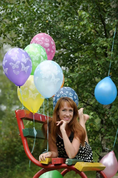 Kobieta w sukience w kropki w parku z balonami latem — Zdjęcie stockowe