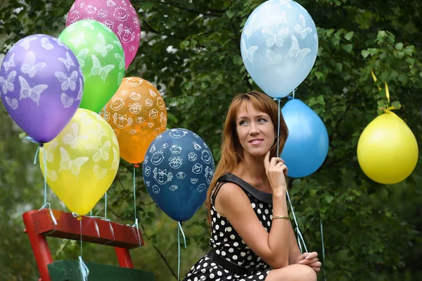 Parkta benekli elbiseli bir kadın. Yazın elinde balonlarla. — Stok fotoğraf