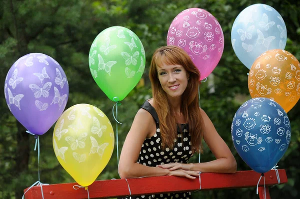 Vrouw in polka-dot jurk in een park met ballonnen in de zomer — Stockfoto
