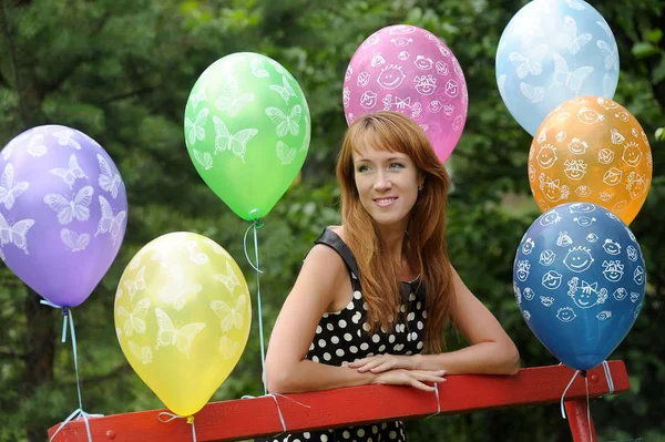 Frau im gepunkteten Kleid in einem Park mit Luftballons im Sommer — Stockfoto