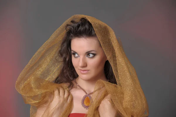 Portrait d'une belle femme brune dans une cape dorée — Photo