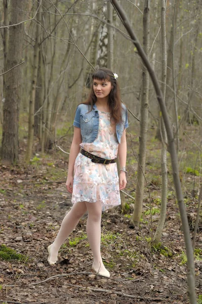 Una ragazza in un abito leggero e giacca di jeans nella foresta tra i — Foto Stock