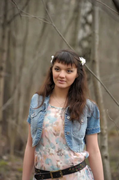 A girl in a light dress and denim jacket in the forest among the — Stock Photo, Image