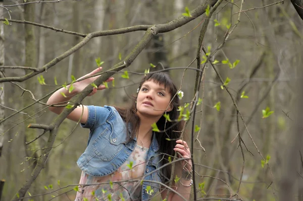 A girl in a light dress and denim jacket in the forest among the — Stock Photo, Image