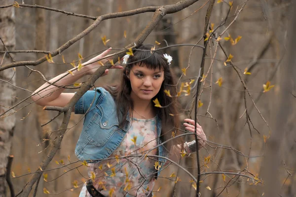 A girl in a light dress and denim jacket in the forest among the — Stock Photo, Image