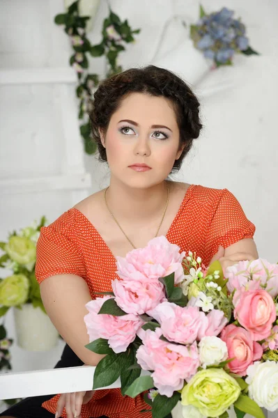 Beautiful brunette in a red blouse with peonies — Stock Photo, Image