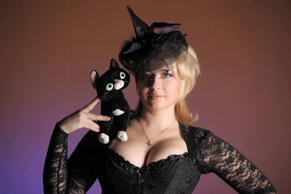 Loira no estúdio e um brinquedo gato preto, Halloween — Fotografia de Stock