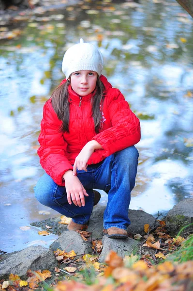 Girl in a red jacket squatting — Stock Photo, Image