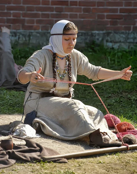 Una mujer en un traje medieval se dedica a la costura de la h — Foto de Stock