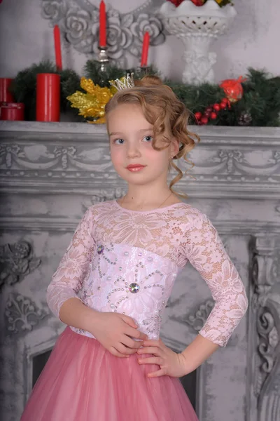 Niña en un vestido rosa junto a la chimenea — Foto de Stock