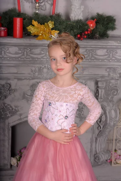 在壁炉旁的粉红色礼服的年轻女孩 — 图库照片