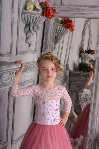 Niña en un vestido rosa junto a la chimenea —  Fotos de Stock