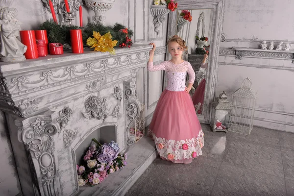 Young girl in a pink dress by the fireplace — Stock Photo, Image