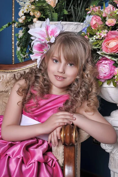 Bambina in abito rosa tra i fiori in studio su t — Foto Stock
