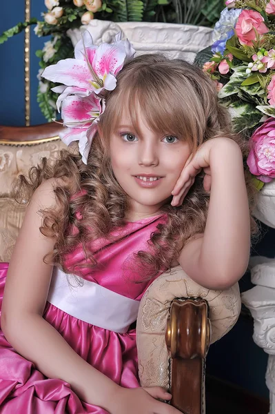 Niña en un vestido rosa entre las flores en el estudio en t — Foto de Stock