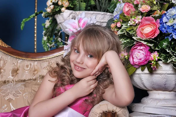 Niña en un vestido rosa entre las flores en el estudio en t —  Fotos de Stock