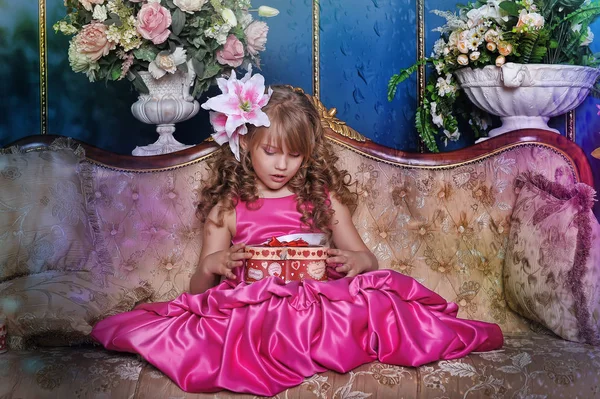 Menina bonito em um vestido rosa entre as flores no estúdio — Fotografia de Stock