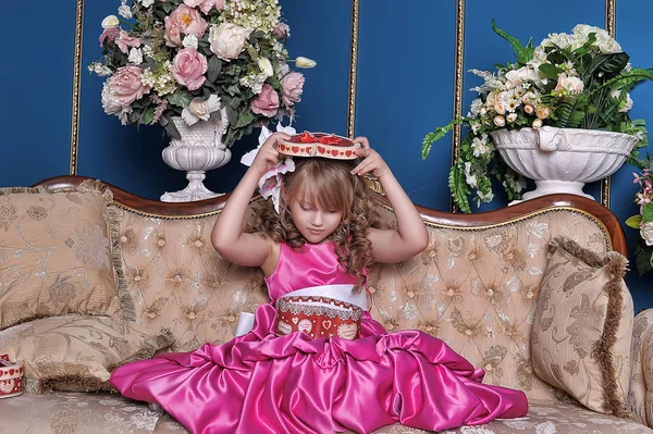 Cute little girl in a pink dress among the flowers in the studio — Stock Photo, Image