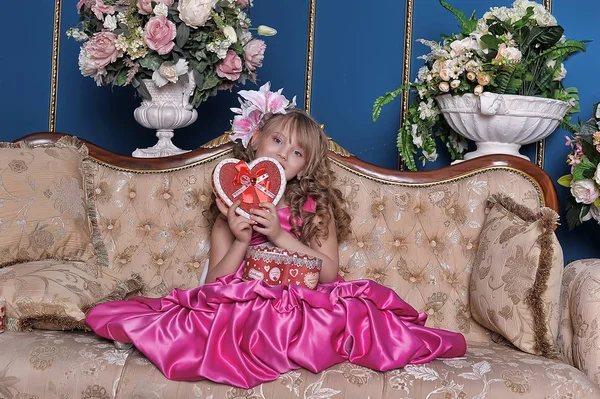 Linda niña en un vestido rosa entre las flores en el estudio — Foto de Stock