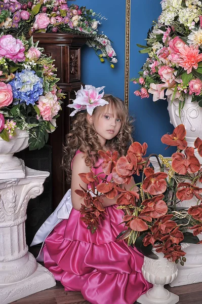 Holčička v růžové princezně mezi květinami v — Stock fotografie