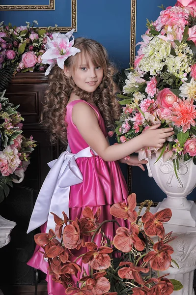 Little girl in a pink princess dress among the flowers in the st — Stock Photo, Image