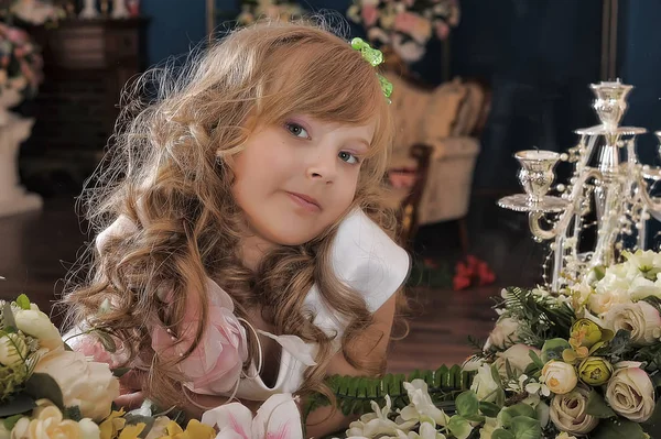 Porträtt av en söt flicka med lockar bland blommor — Stockfoto