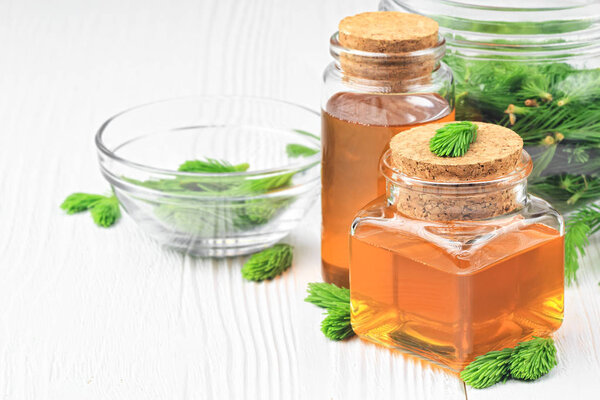 Homemade pine cough syrup for dry irritating throat coughs. Made from green young pine buds and honey.Alternative medicine concept on white wooden table (selective focus).