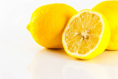 Üç limon, ikiye bölünmüş bir dilim taze ve lezzetli görünüyor. Beyaz bir arkaplanda