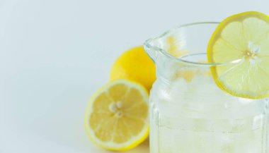 Limon dilimleriyle süslenmiş buzlu limon suyu beyaz bir arka planda ikiye bölünmüş.