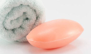 Bir kalıp sabun ve temiz beyaz havlu hijyen için beyaz bir sahnede..