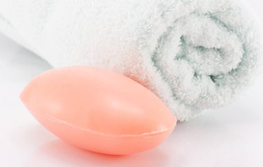 Bir kalıp sabun ve temiz beyaz havlu hijyen için beyaz bir sahnede..