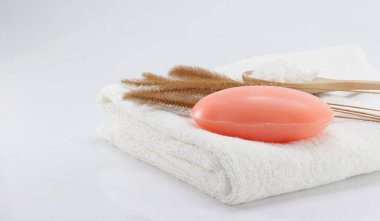 Temiz beyaz havlular ve kuru otla beyaz bir sahnede hijyen için sabun..