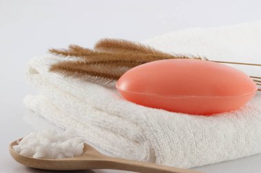 Temiz beyaz havluların üzerindeki sabun, kurutulmuş çimen ve beyaz sahnede temizlik için tuz fırçası..