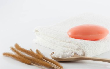 Temiz beyaz havluların üzerindeki sabun, kurutulmuş çimen ve beyaz sahnede temizlik için tuz fırçası..