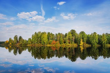 Açık bir günde sudaki ağaçların yansımasıyla güzel bir sonbahar manzarası. Rusya, Urallar