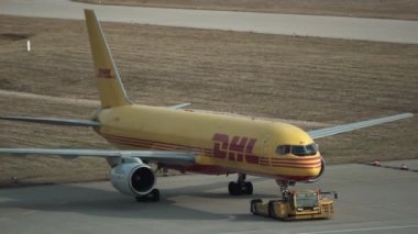 Schkeuditz, Almanya - 10 Nisan 2018: El closeup çekim havaalanında tesis sıralama onların paket yanında pistte taxied bir Dhl kurye kargo jeti.