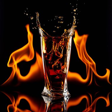 Siyah bir viski bardağına alevler saçar.