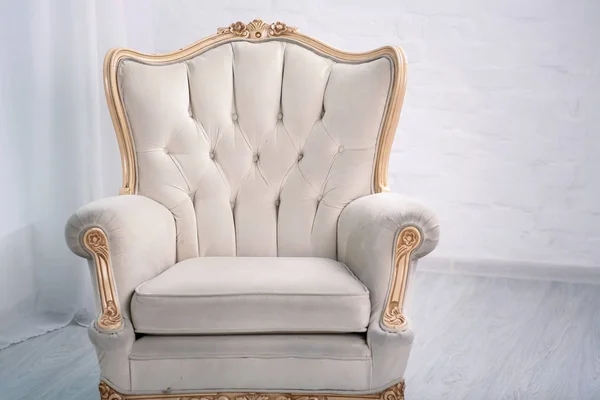 Beige leather wood armchair with golden decor in a white living room