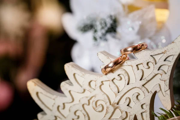 Gold wedding rings on a white wooden Christmas tree, close-up. Christmas concept.