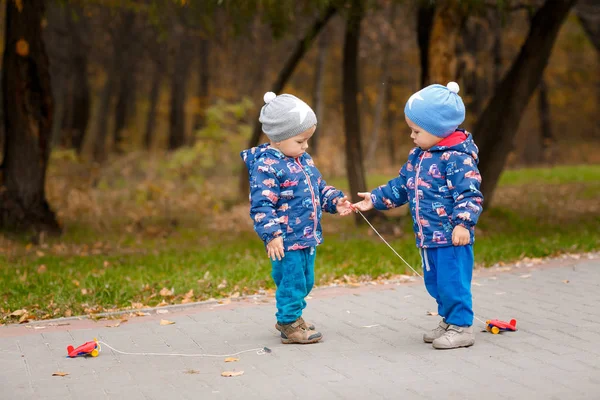 双胞胎在秋园玩玩具车 — 图库照片